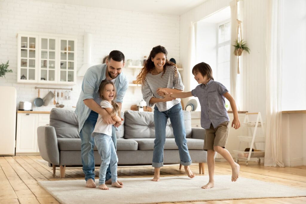 A family smiling and playing in the living room of an El Paso new construction home.