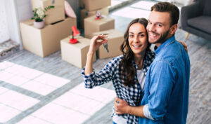 A couple hugging and holding up house keys to their new affordable home in El Paso.