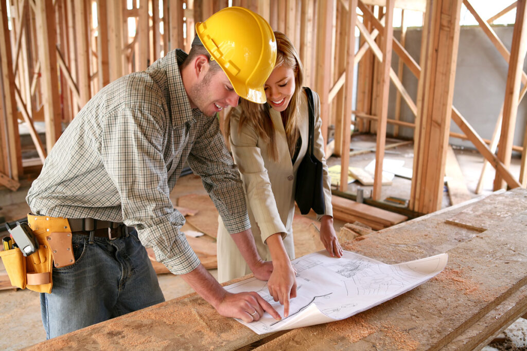 A home builder reviewing building plans with a woman in El Paso.
