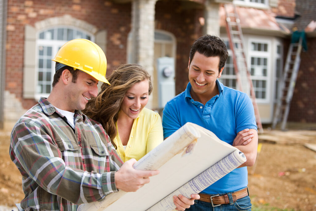A new construction builder showing floor plans to two people in El Paso.